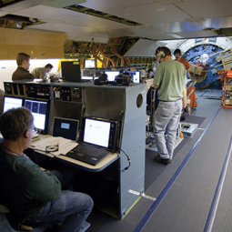 View aft on main deck during a SOFIA science flight, showing mission operations and science team personnel and consoles. 