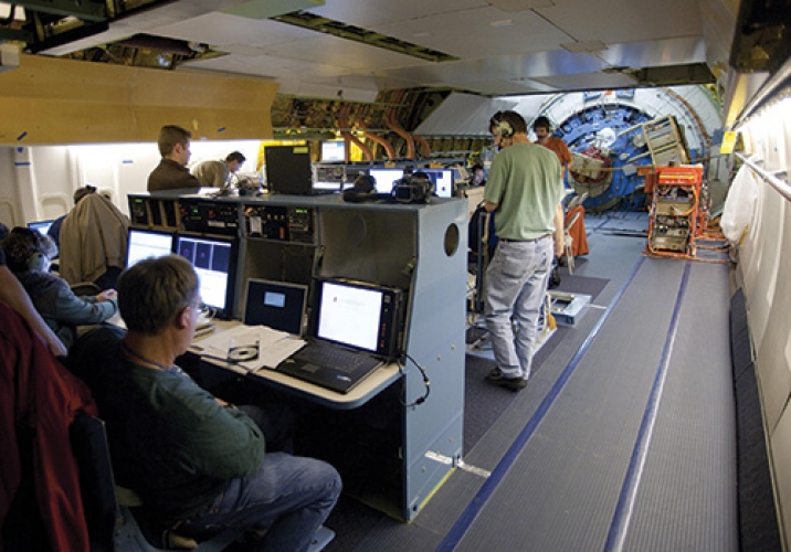 View aft on main deck during a SOFIA science flight, showing mission operations and science team personnel and consoles. 